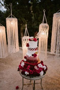 a three tiered cake sitting on top of a table covered in red and white flowers