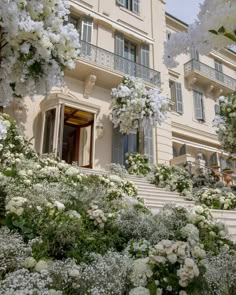 white flowers are blooming in front of a large building with stairs and balconies