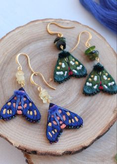 three butterfly shaped earrings sitting on top of a piece of wood