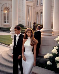 a woman in a white dress standing next to a man in a tuxedo