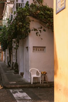 a white chair sitting on the side of a street next to a tall yellow building