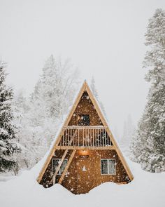 a wooden cabin in the snow surrounded by trees