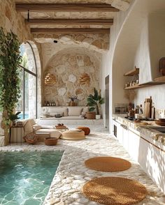 an indoor swimming pool surrounded by stone walls and flooring with potted plants on either side