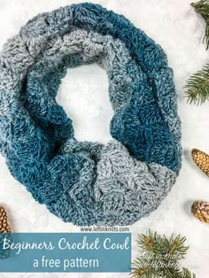 a blue and gray knitted scarf next to pine cones on white snow covered ground