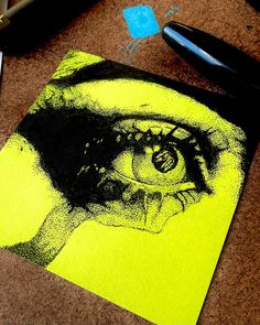 a drawing of a woman's face on a yellow piece of paper next to a pen