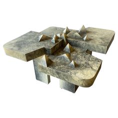 an artistic table made out of concrete with geometric shapes on it's sides and top