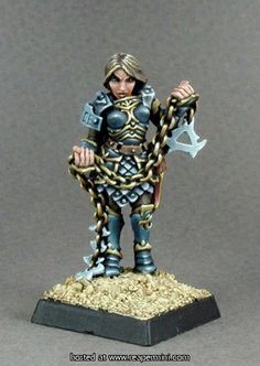 a miniature figurine is posed on a base with chains and hammers in her hands