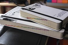 two notebooks are stacked on top of each other in front of bookshelves