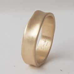 a gold wedding ring is shown on a white surface with the word love written in it