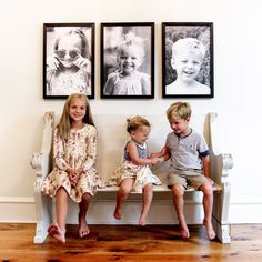 three children sitting on a bench in front of pictures