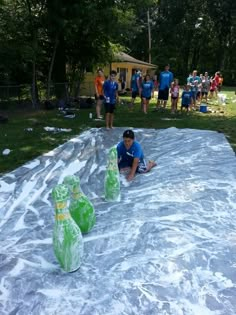 a man sitting on top of a tarp covered field next to green vases