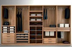 an open closet with drawers and clothes hanging on the wall, including shirts and pants