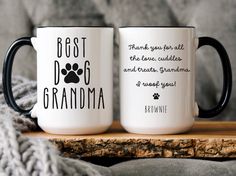 two black and white coffee mugs sitting on top of a wooden table next to a gray blanket