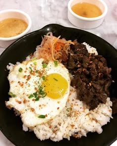 a black plate topped with rice, meat and an egg