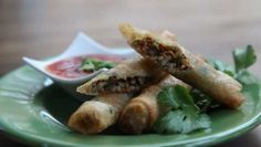 some food is on a green plate and ready to be eaten with dipping sauce in the background