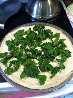 a pizza sitting on top of a metal pan covered in green leafy toppings