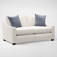 a white couch with two blue pillows on the armrests and one black pillow