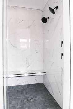 a bathroom with white marble walls and floor, black faucets on the shower head