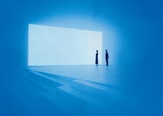 two people standing in an empty room with bright blue light coming through the wall and floor