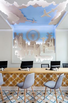 an office with blue and white walls, wooden desks and chairs in front of a mural on the wall