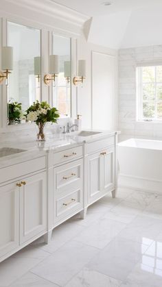 a white bathroom with two sinks and a bathtub in the corner, along with marble flooring