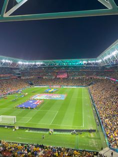 a stadium filled with lots of people watching a soccer game on the field at night