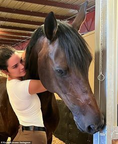 a woman standing next to a brown horse