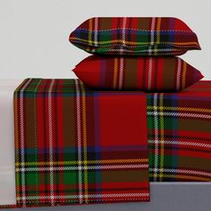 three plaid pillows are stacked on top of each other, one is red and the other is green