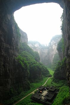 an aerial view of a small village nestled in the side of a mountain with green grass