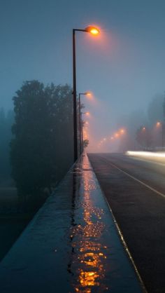 the street lights shine brightly on a foggy night in an area that has been flooded with water