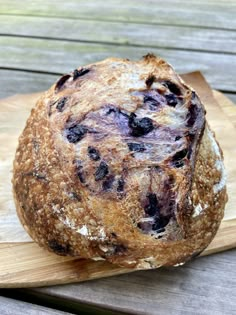 a loaf of blueberry bread sitting on top of a wooden cutting board next to a knife