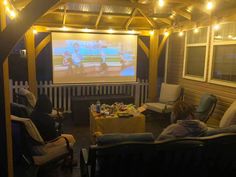 two people sitting in chairs watching a movie on the screen at night with lights around them