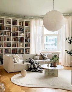 a living room filled with furniture and bookshelves next to a white rug on top of a hard wood floor