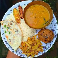 a white plate topped with food next to a bowl of soup and french fries on top of it