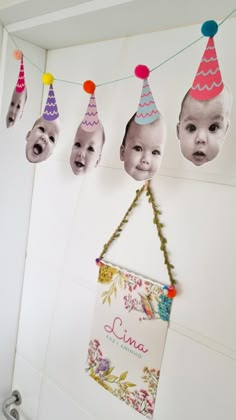 a baby's first birthday photo hanging on the wall with party hats attached to it