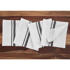 four white and black striped napkins sitting on top of a wooden table