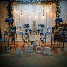 a table topped with blue flowers and white cake next to a sign that says amaror