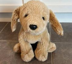 a stuffed dog sitting on the floor in front of a door with its eyes closed