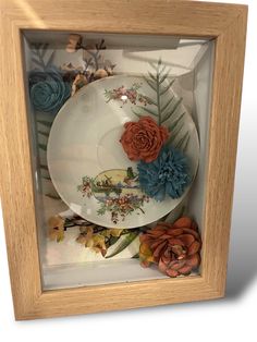 a white plate with flowers and leaves in a wooden frame