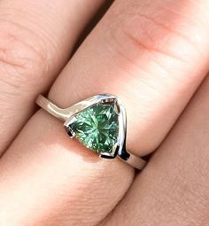 a woman's engagement ring with a green diamond in the shape of a heart