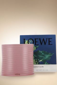 a pink candle sitting on top of a table next to a box of loewe candles