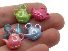 four miniature teapots are sitting in the palm of someone's hand