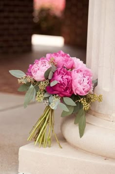 a bouquet of pink flowers sitting on top of a pillar