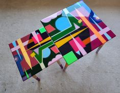 a table made out of colorful pieces of art on top of a carpeted floor