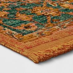 an orange and green area rug on a white surface with no people in the photo