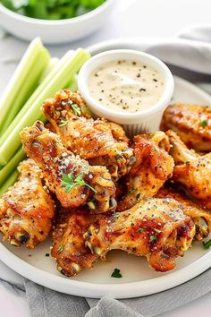 chicken wings on a plate with dipping sauce and celery sticks next to it