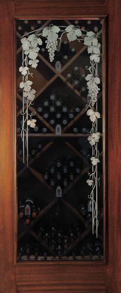 a wine rack with several bottles in it and vines hanging from the glass front door