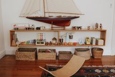 a toy boat is sitting on top of a shelf with baskets and toys in front of it