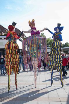 some people are walking down the street dressed in colorful costumes and hats with streamers on their heads