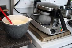 a bowl of liquid sitting on top of a stove next to an electric blender